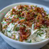 Creamy caramelized onion dip with sour cream and fresh chives, perfect for dipping chips or vegetables at your next gathering.