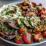 Vibrant array of grilled zucchini, bell peppers, and eggplant served with smooth, homemade hummus for a Mediterranean-inspired dish.  