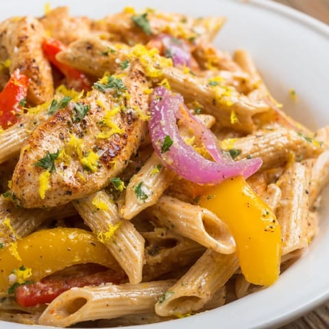 A steaming bowl of Creamy Cajun Chicken Pasta Lite garnished with lemon zest, ready for a comforting dinner.