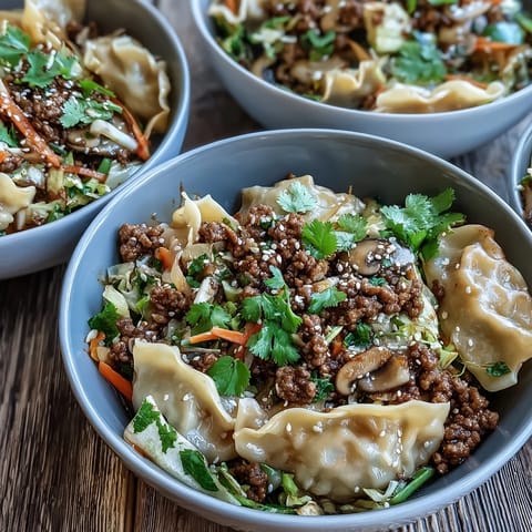 A steaming bowl of Potsticker Noodle Bowls topped with green onions and sesame seeds.
