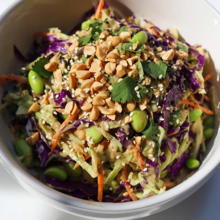 This colorful Crunchy Thai Peanut Salad features crisp vegetables, edamame, and chopped peanuts, served fresh with lime wedges.  
