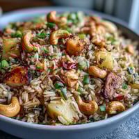 Vibrant pineapple chicken fried rice with juicy pineapple chunks, tender chicken, crunchy cashews, and colorful vegetables in a savory sauce.  
