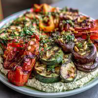 A colorful grilled vegetable platter with creamy hummus, perfect for summer gatherings or healthy snacking.  